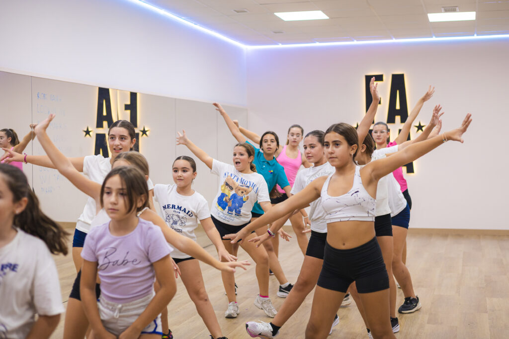Grupo de alumnas ensayando una coreografía con los brazos extendidos en FAMA
